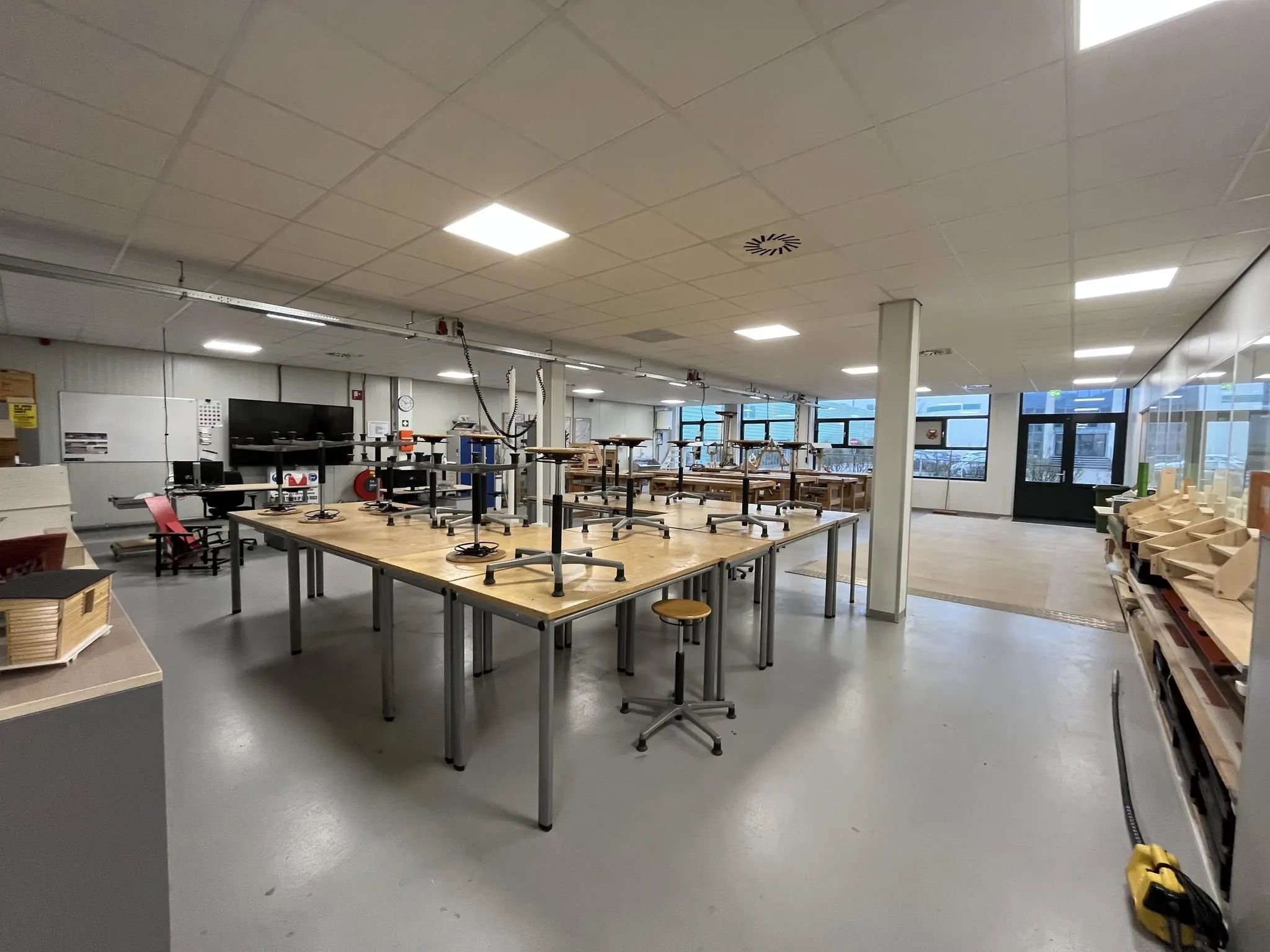 Ruim lokaal met werkbanken, opgestapelde krukken en diverse houtbewerkingsprojecten aan de Niels Bohrweg.